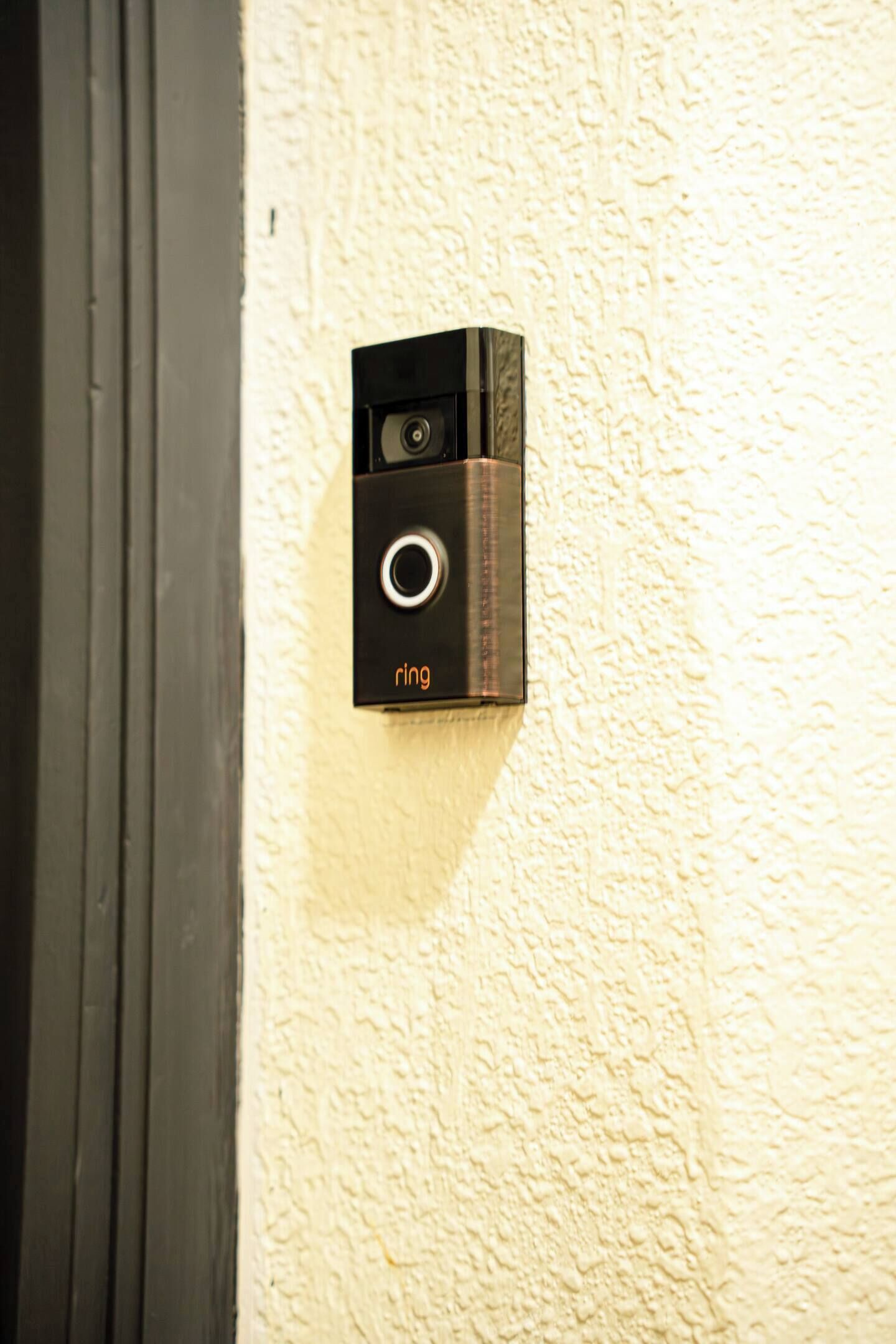 Una cámara de seguridad fijada en una pared con textura, cerca de una puerta.