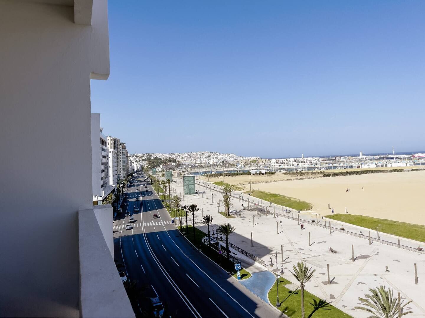 Un paysage urbain côtier avec une large route, une plage et des immeubles résidentiels.
