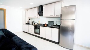 A modern kitchen with white cabinets, a stainless steel refrigerator, and a black countertop. - The perfect coastal getaway, just steps from the beach, with a private balcony, open living area. (Tangier)