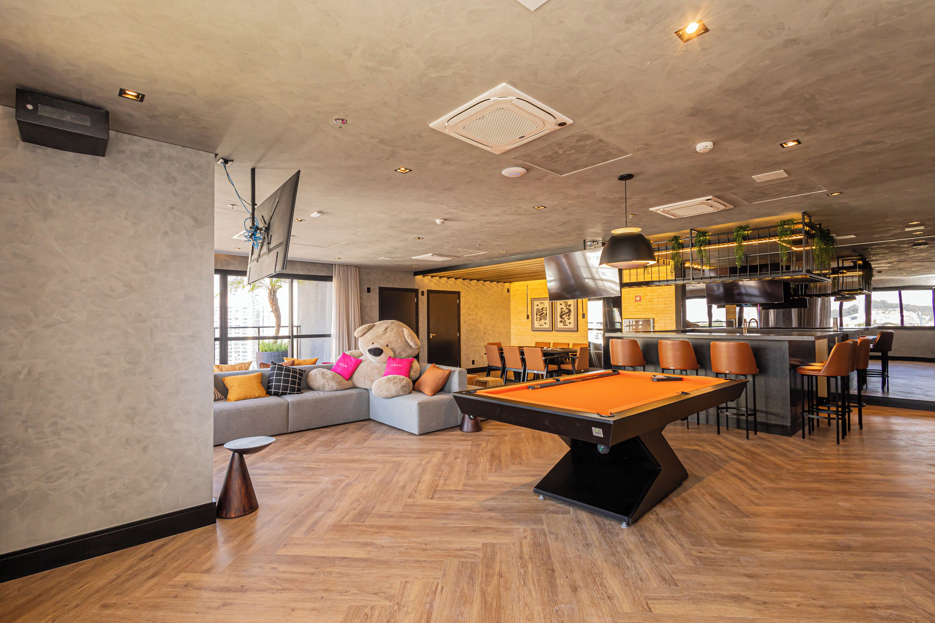 Un espacio interior moderno con mesa de billar, zona de estar y bar.