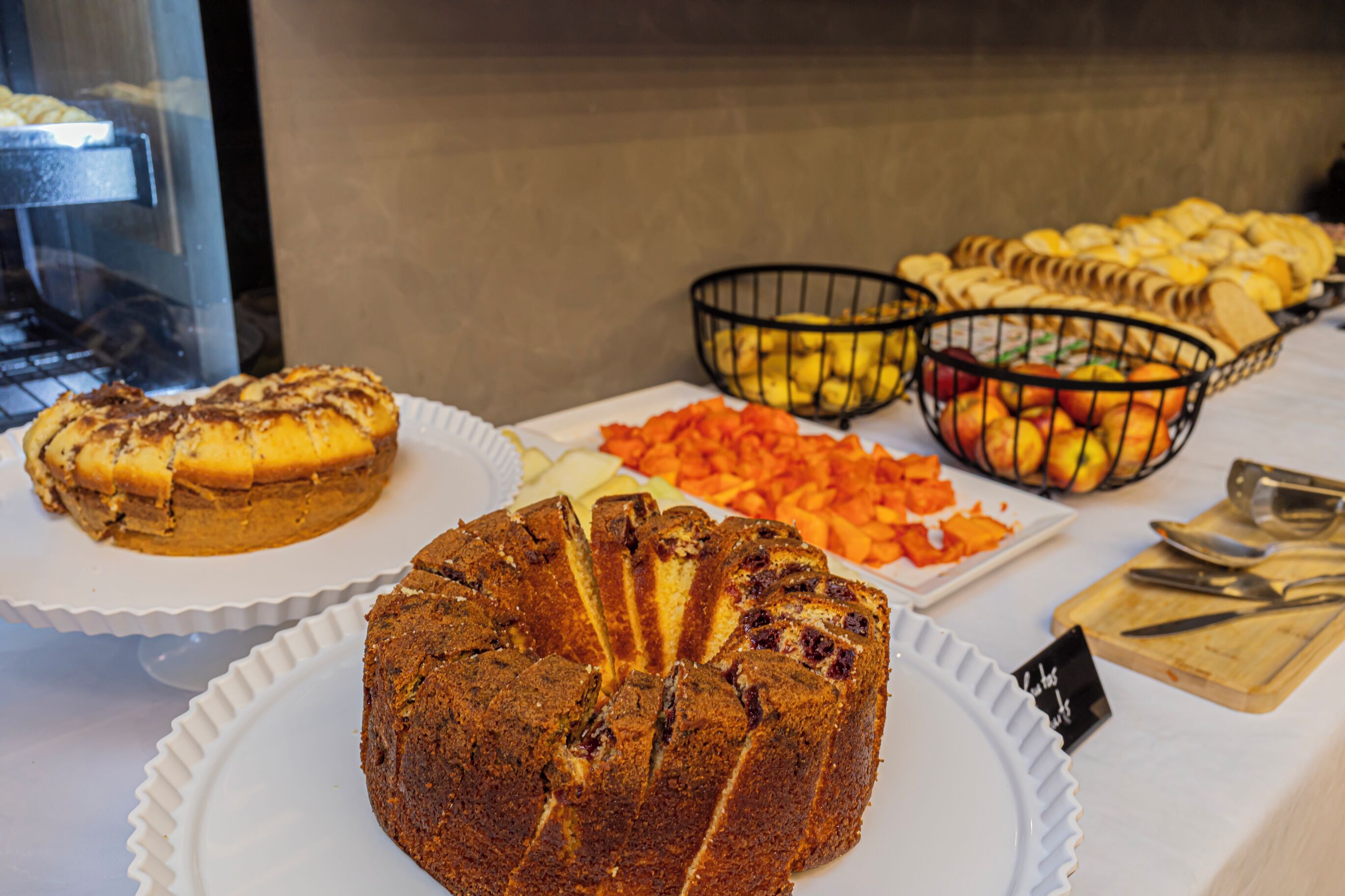 Un bufé con diversos alimentos, incluyendo pastel, frutas y verduras.