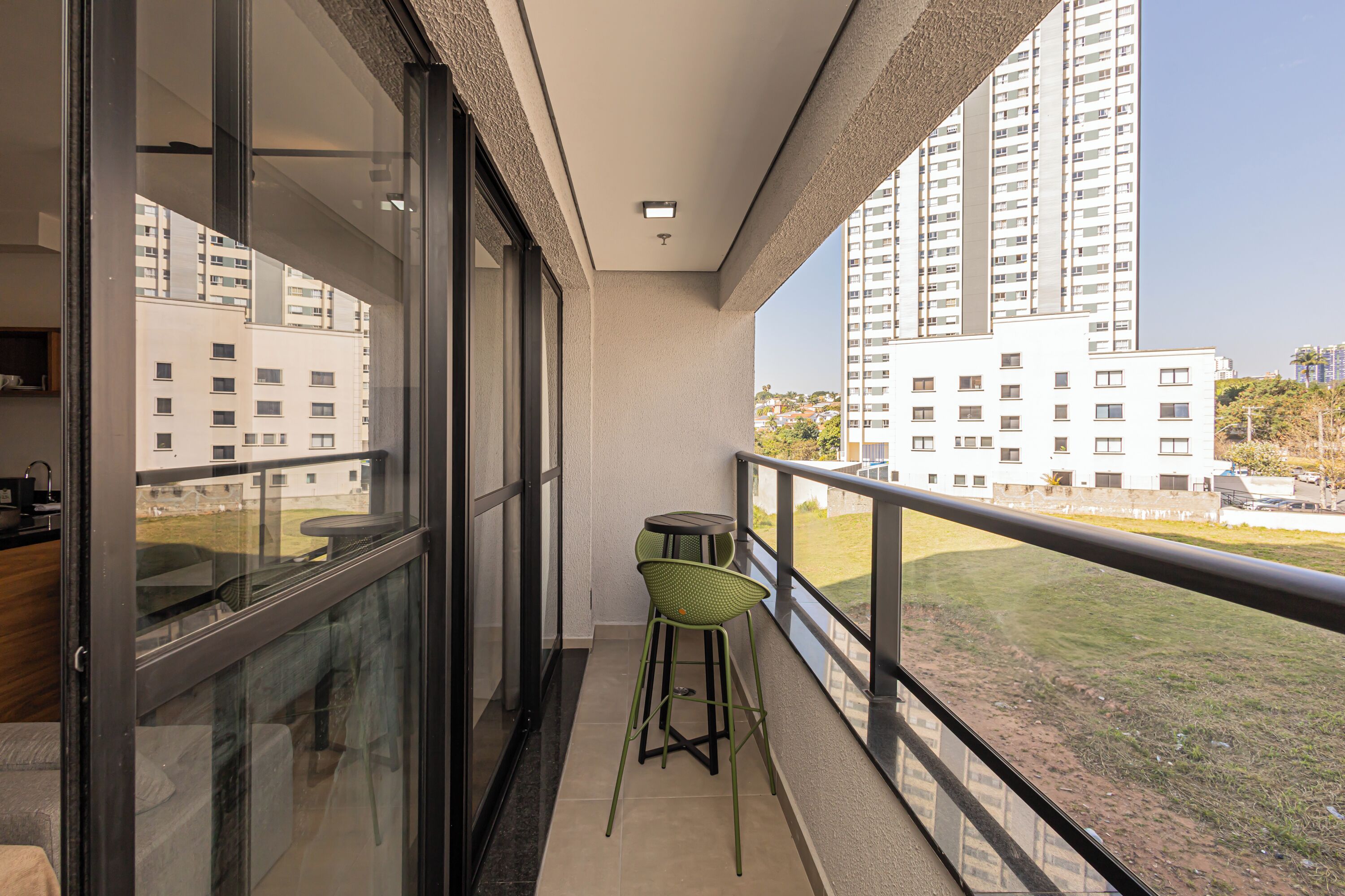 A balcony with a glass door, a small table, and a green chair.
