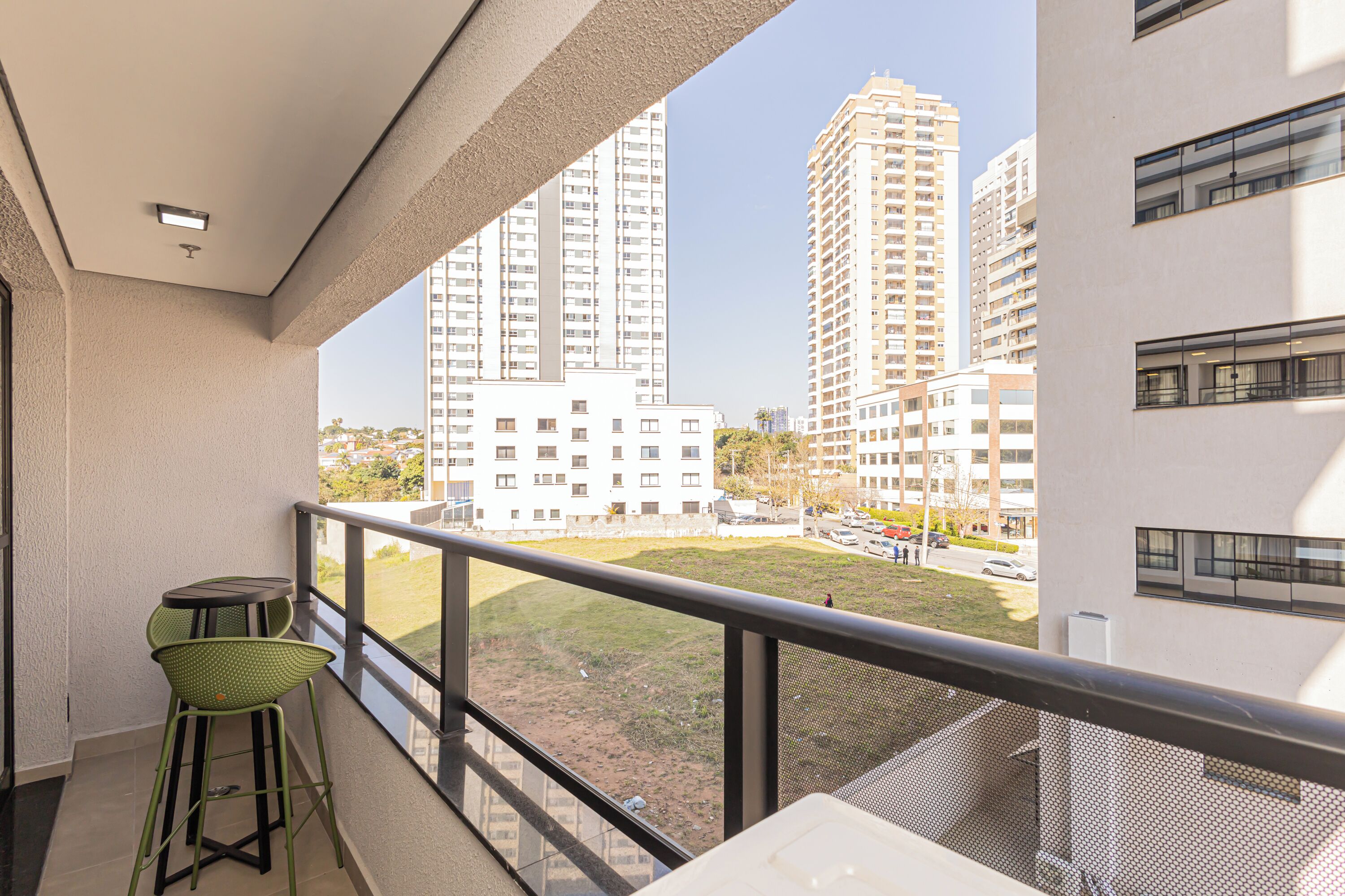 A balcony with a view of tall residential buildings, a small table, and a chair.