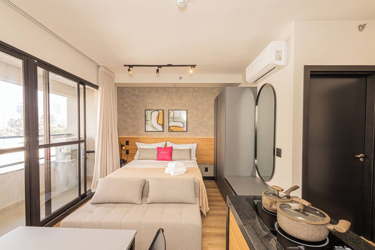 Une chambre d’hôtel moderne, dotée d’un grand lit, d’un bureau, d’un miroir et offrant une vue sur la ville.