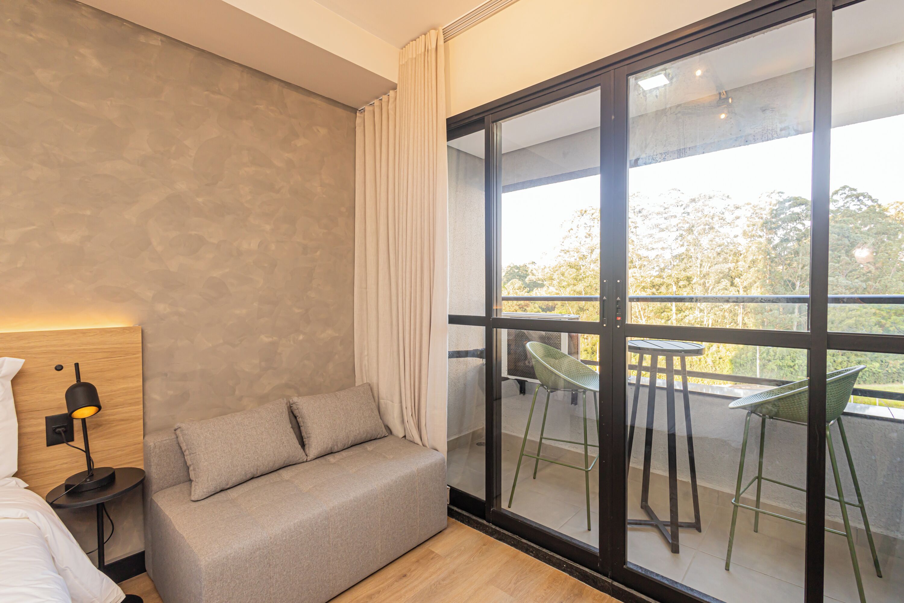 A modern room with a sofa, a small table, and a balcony with chairs.