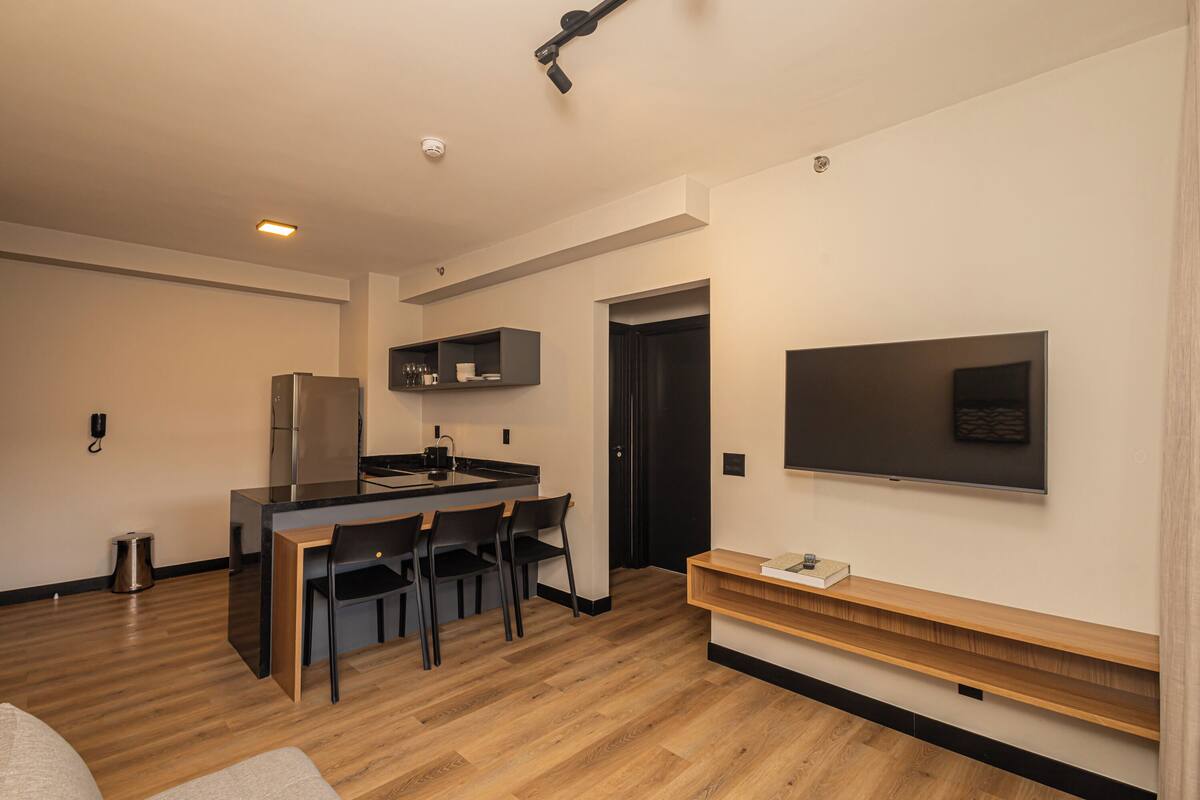 Une cuisine moderne avec un îlot central, des chaises noires et un réfrigérateur encastré.