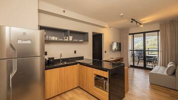 A modern kitchen with a built-in oven, a refrigerator, and a microwave. There is a dining area with a table and chairs, and a sofa.