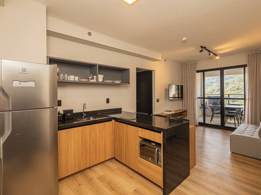 A modern kitchen with a built-in oven, a refrigerator, and a microwave. There is a dining area with a table and chairs, and a sofa.