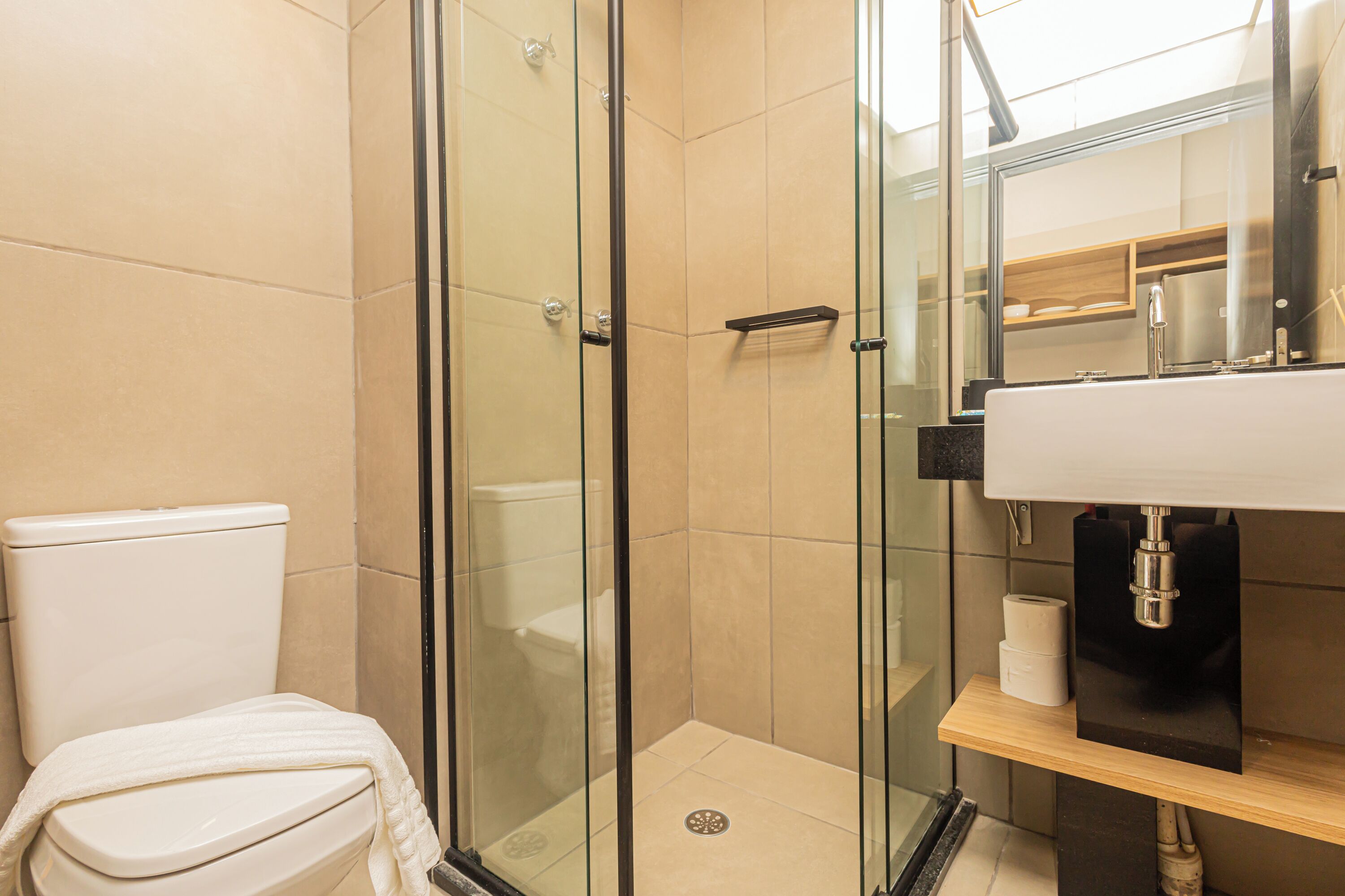 A modern bathroom with a glass shower enclosure, a toilet, and a sink with a mirror.