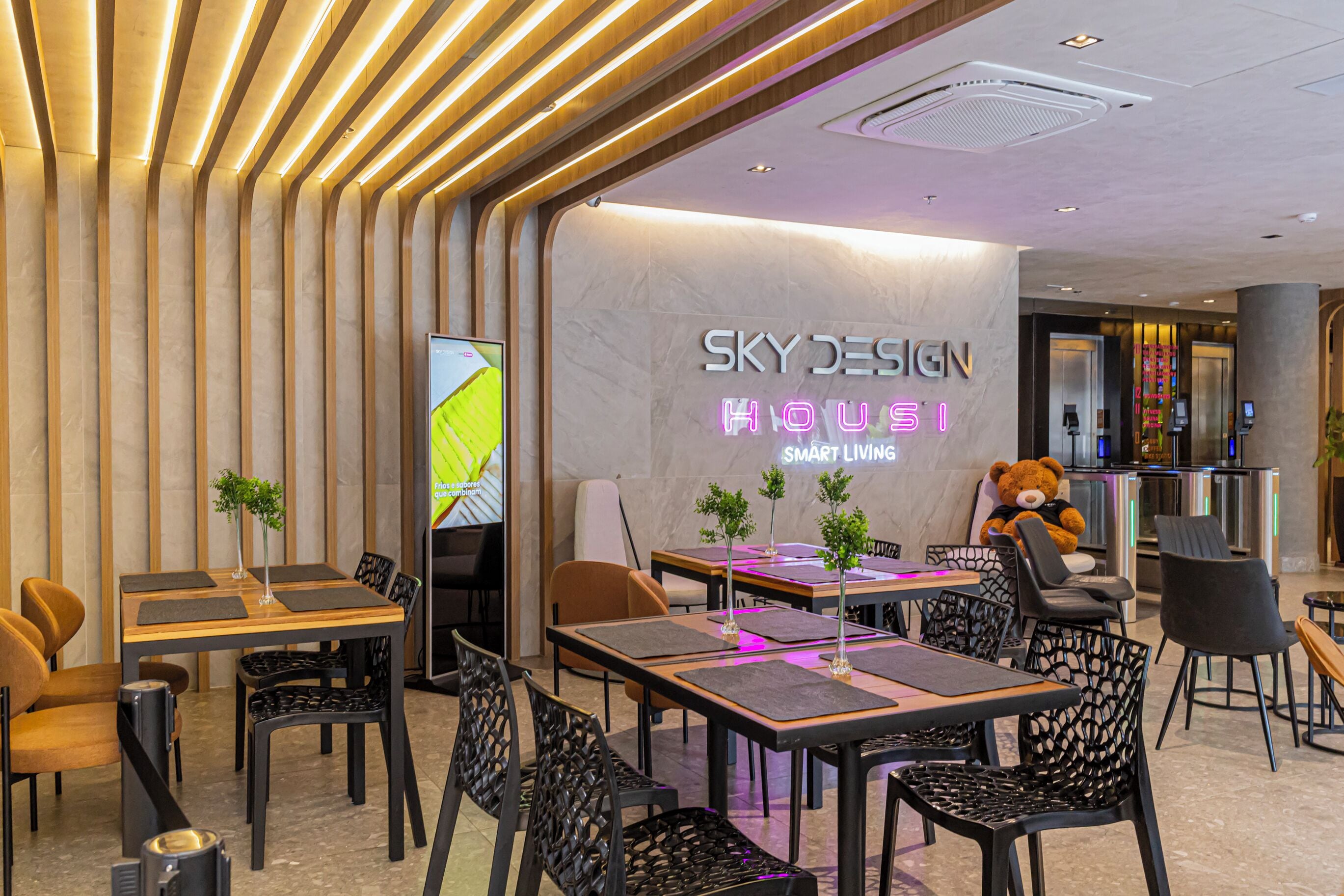 A modern interior with tables and chairs, a teddy bear decoration, and a sign reading 'SKY DESIGN HOUSE'.