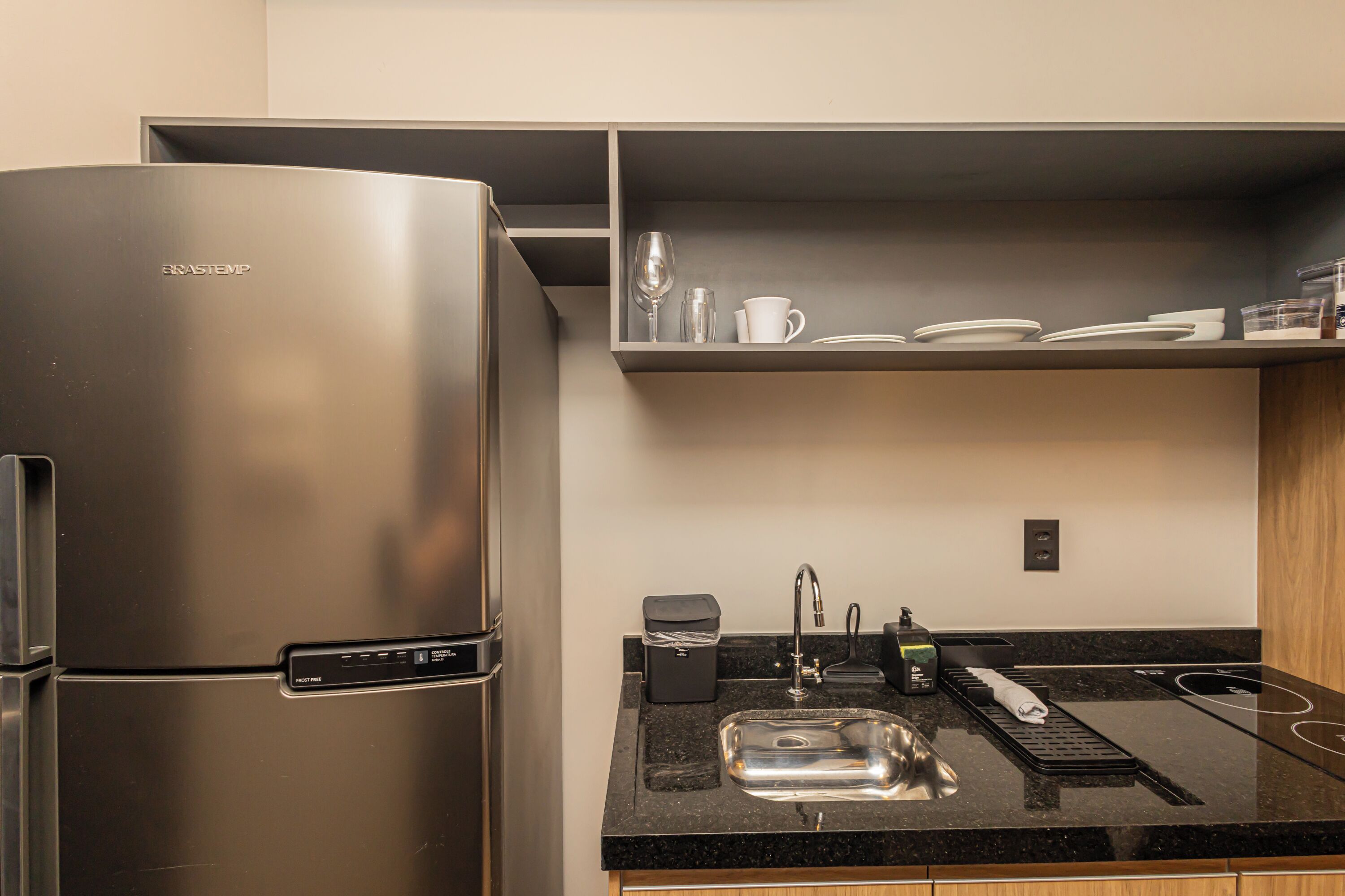 A kitchen with a stainless steel refrigerator, a sink, and a countertop with a coffee machine and a toaster.