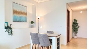 Un comedor moderno con una mesa, sillas, una lámpara de pie y plantas en macetas.