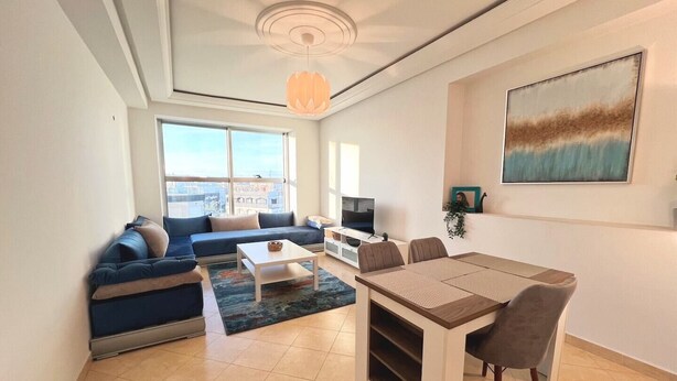 Una sala moderna con sofá, mesa de centro, mesa de comedor y televisor.