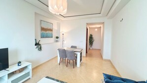 Una sala de estar moderna con televisor, una mesa de comedor y un sofá.