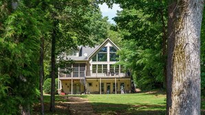 A two-story house with a large balcony, surrounded by trees. - Beautiful Lake Home/Private Dock (Gainesville)