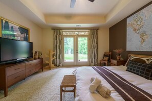 A hotel room with a large bed, a television on a wooden cabinet, a small table with a vase, and a world map on the wall. - Beautiful Lake Home/Private Dock (Gainesville)