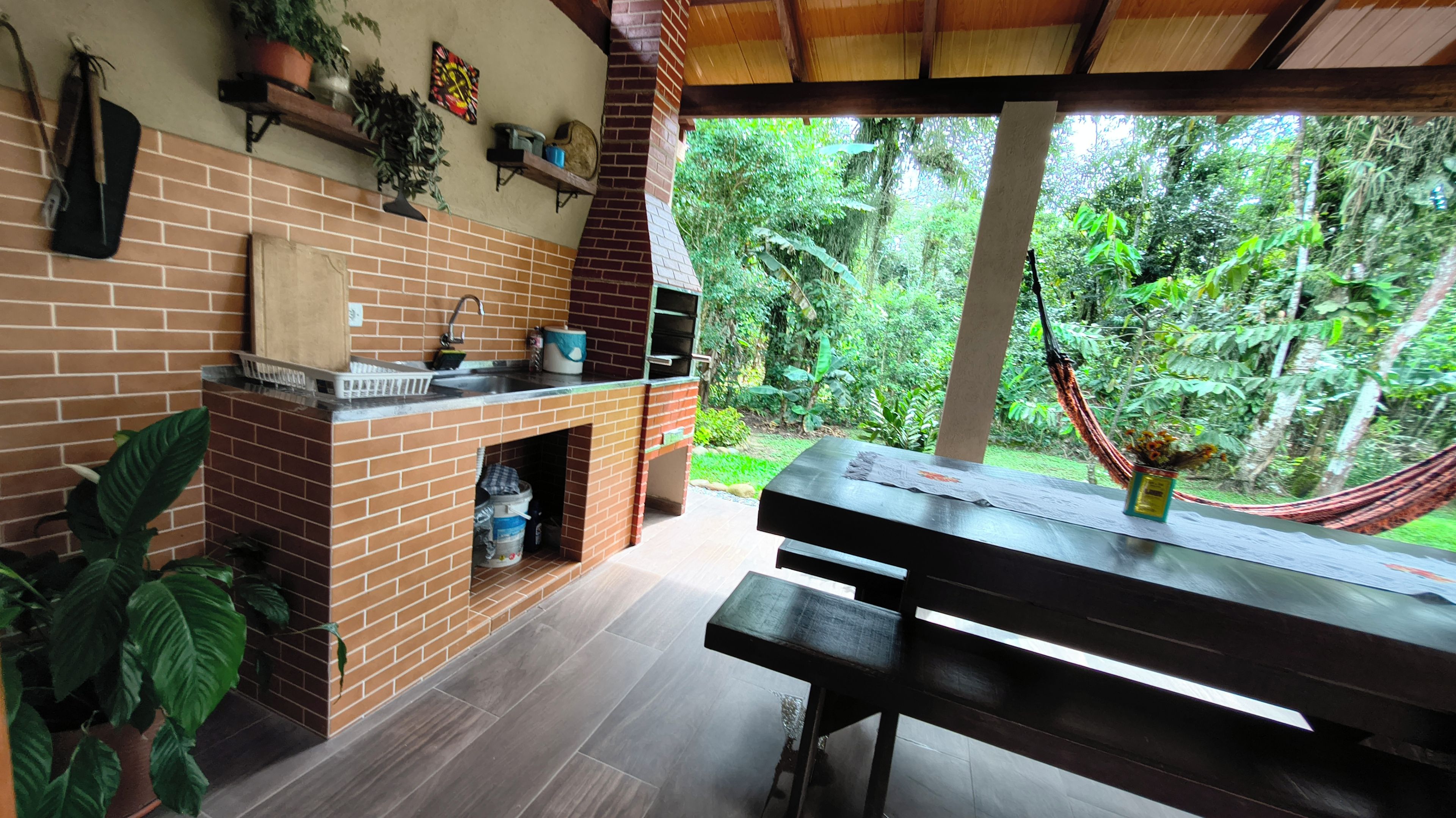 Un área de cocina al aire libre con chimenea de ladrillo, un lavamanos y una mesa de comedor.