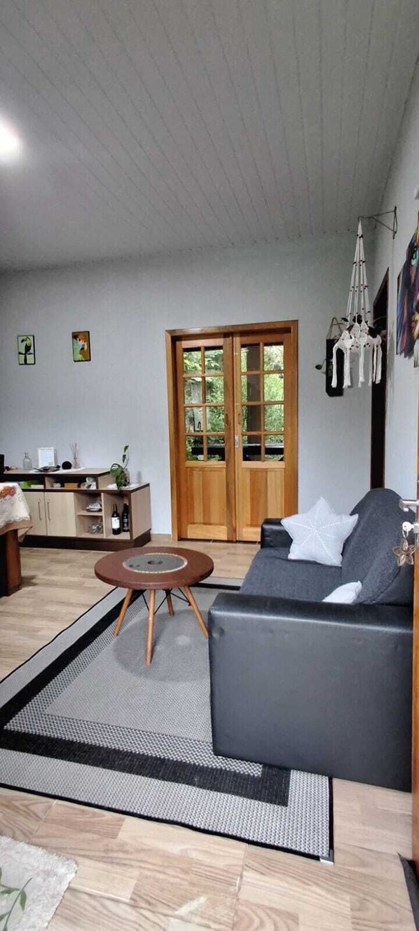 A living room with a sofa, a round coffee table, a wooden cabinet, and a door leading to a balcony.