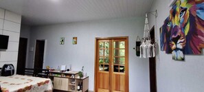 A room with a bed, a wooden cabinet, a desk, a chair, a door with glass panels, and a wall with a colorful painting. - Beautiful House! Enjoy nature and cool off in the pool. (Morretes)