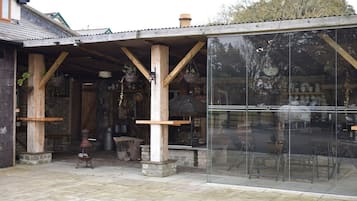 A rustic building with a covered outdoor area, wooden beams, and a glass storefront.