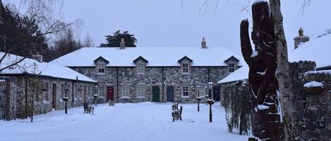A stone building with multiple windows and a snow-covered roof.