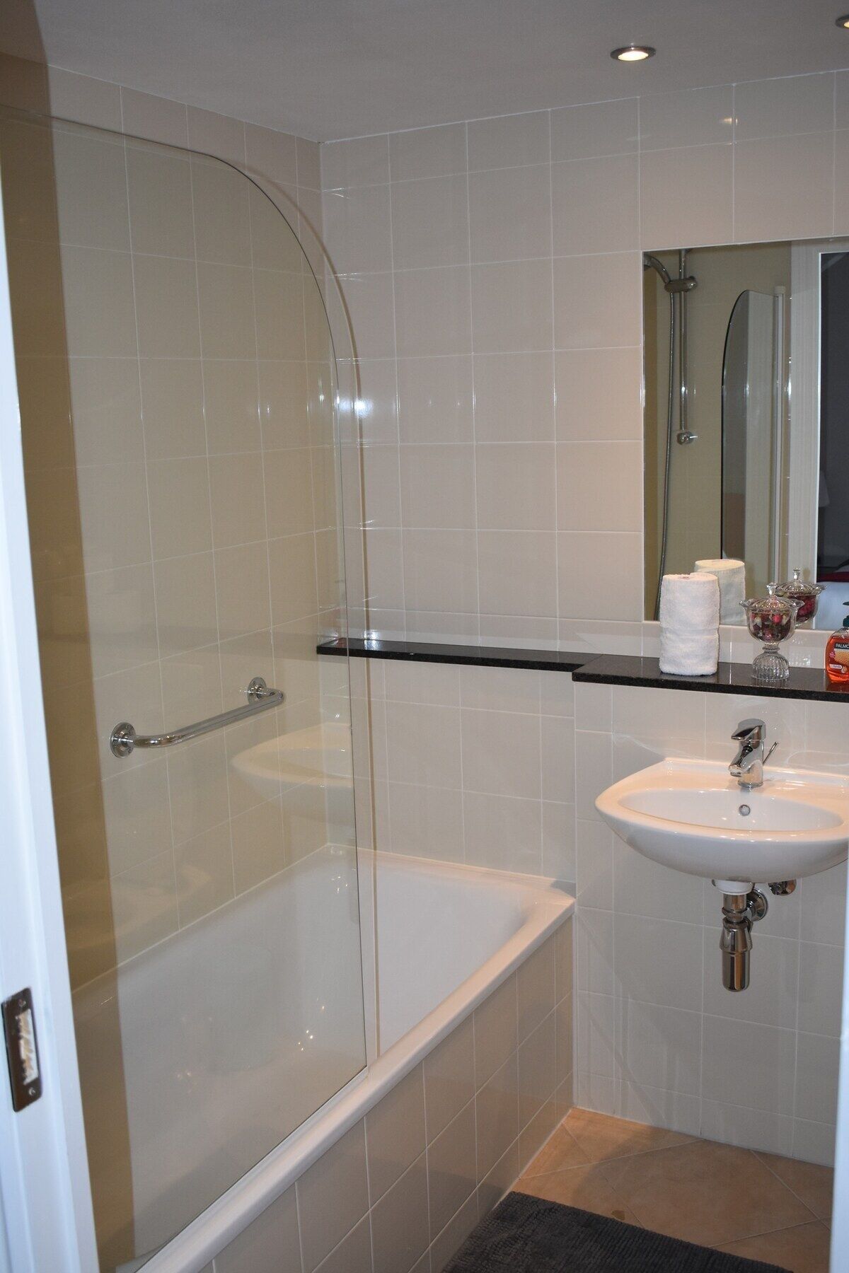 A modern bathroom with a glass-enclosed shower, a bathtub, and a sink with a mirror above it.