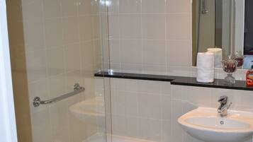 A modern bathroom with a glass-enclosed shower, a bathtub, and a sink with a mirror above it.
