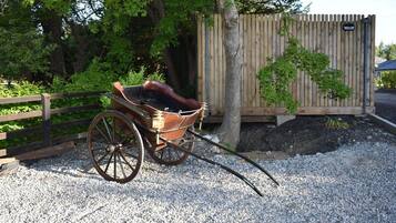 A wooden carriage with a leather seat parked on gravel.