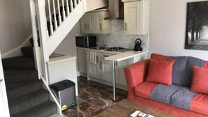 A compact living space with a kitchen, a sofa, a coffee table, and a staircase.