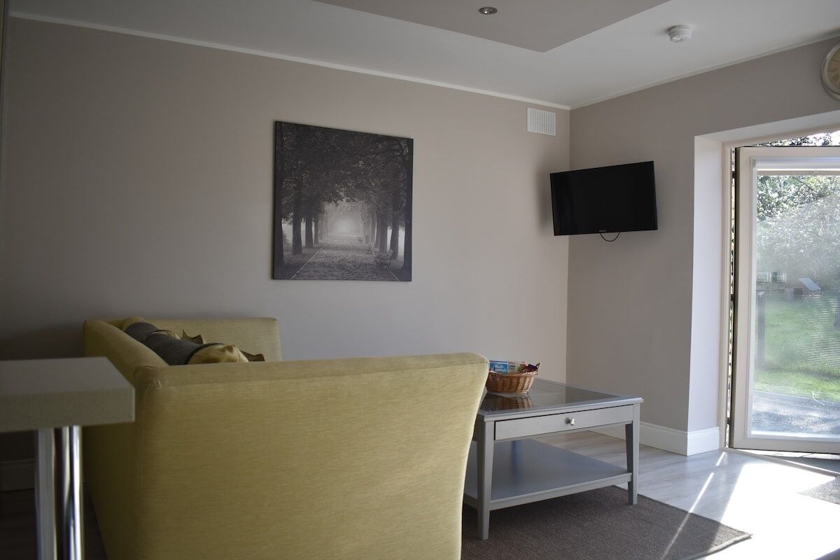 Een woonkamer met een bank, een flatscreen televisie, een schilderij en een tafel met een mand.