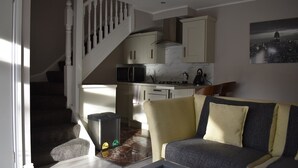 A living room with a sofa, a coffee table, and a staircase leading to a kitchen.
