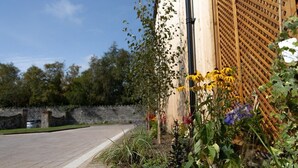 Un jardin agrémenté de diverses plantes et fleurs, un mur de pierre et une clôture en bois.