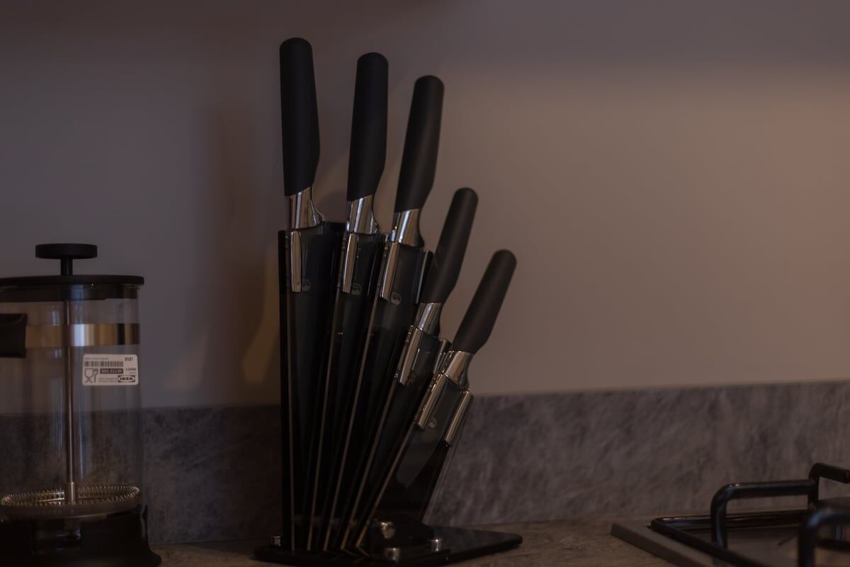 A kitchen counter with a knife block holding several knives.