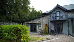 A stone building with a balcony, a patio area with chairs, and a well-maintained garden. - No. 5 The Stone House at Alensgrove (Leixlip)