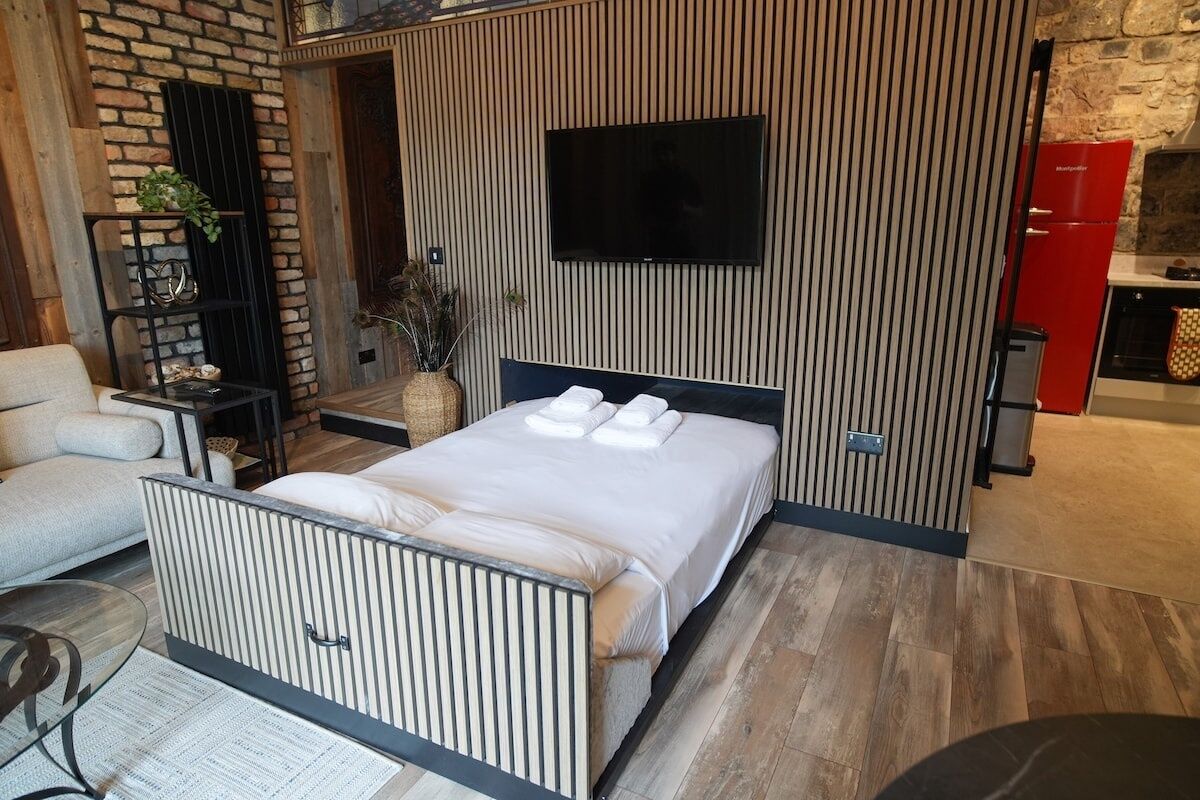 Une chambre moderne avec un lit, un téléviseur, un appareil électroménager rouge et un mur en briques.
