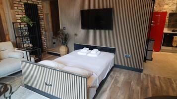 Une chambre moderne avec un lit, un téléviseur, un appareil électroménager rouge et un mur en briques.