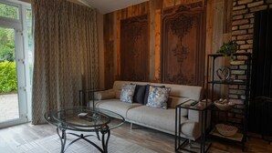 A living room with a sofa, glass coffee table, and a brick wall. - No. 5 The Stone House at Alensgrove (Leixlip)
