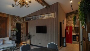 A modern living room with a fireplace, a dining area with a black table, and a kitchen with a red refrigerator. - No. 5 The Stone House at Alensgrove (Leixlip)