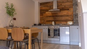 Une cuisine moderne avec des panneaux muraux en bois, une hotte de cuisine en acier inoxydable, un four et un lave-vaisselle.