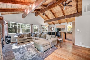 A spacious living room with a large sectional sofa, wooden beams, and a ceiling fan. - Alder Adventure | Family Friendly | Great Location (Truckee)