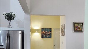 Ett modernt kök med ett kylskåp i rostfritt stål, en hall med gula väggar och en dörr som leder till ett annat rum.