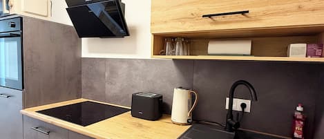 A modern kitchen with a wooden countertop, black sink, and integrated appliances.