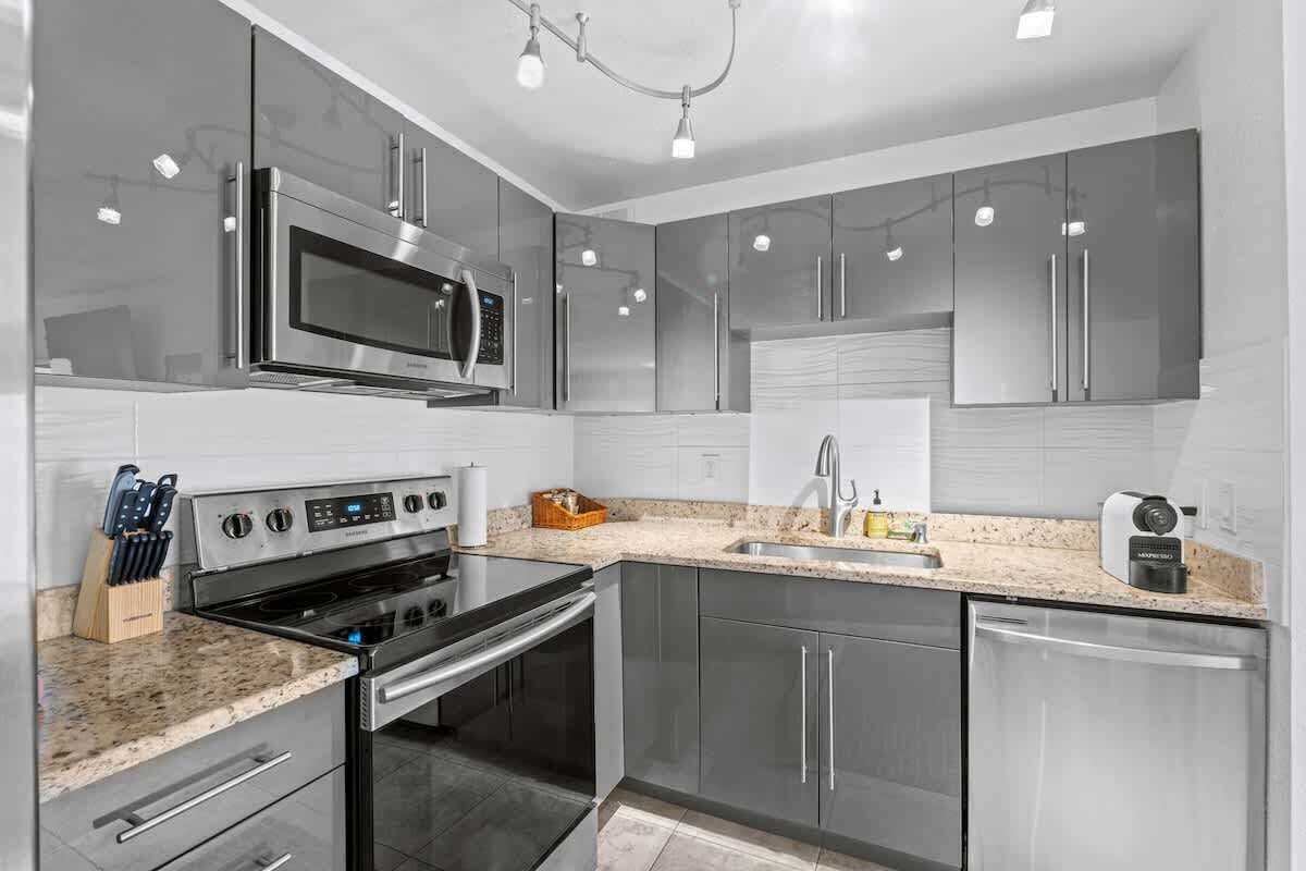 Una cocina moderna con electrodomésticos de acero inoxidable, encimeras de granito y horno empotrado.