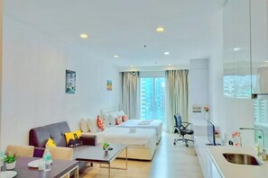 Una habitación de hotel moderna con sofá, dos camas, un escritorio y baño.