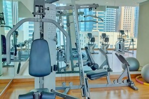 A gym with exercise equipment, large windows, and a view of buildings. - Lila Suite One Bukit Ceylon (Kuala Lumpur)