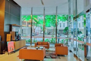 A modern lobby with a reception desk, seating area, and large windows offering a view of the street. - Lila Suite One Bukit Ceylon (Kuala Lumpur)