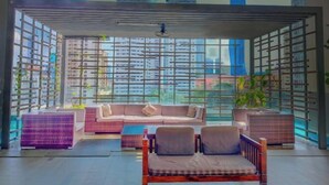 A modern lounge with a view of high-rise buildings, a ceiling fan, and a variety of seating options. - Lila Suite One Bukit Ceylon (Kuala Lumpur)