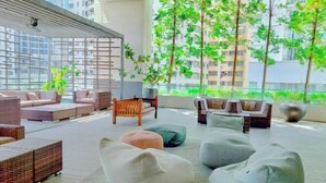 A modern lounge area with seating, a coffee table, and a view of greenery and buildings. - Lila Suite One Bukit Ceylon (Kuala Lumpur)