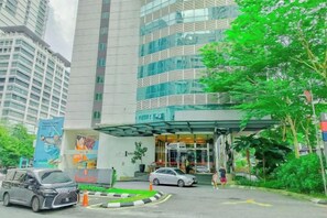 A hotel entrance with a covered entrance, a car parked in front, and a pedestrian pathway. - Lila Suite One Bukit Ceylon (Kuala Lumpur)