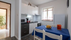 A compact kitchen with white cabinets, a microwave, a stove, and a dining table with chairs.